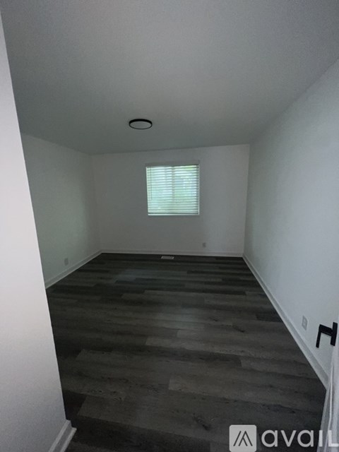 A room with wooden flooring and a window with blinds.