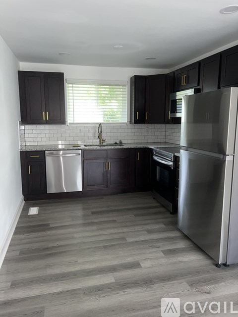 A kitchen with a refrigerator, sink, and cabinets.