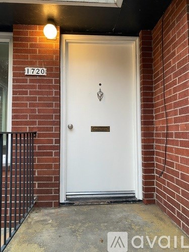 A white door with a black handle and a number 1720 on the wall above it.