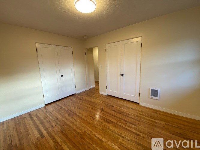 A room with wooden floors and two white doors.