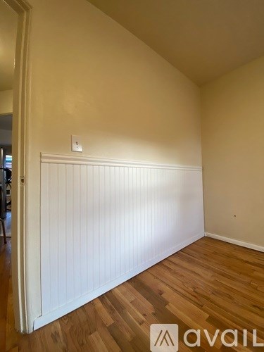 A room with wooden flooring and a white wall.