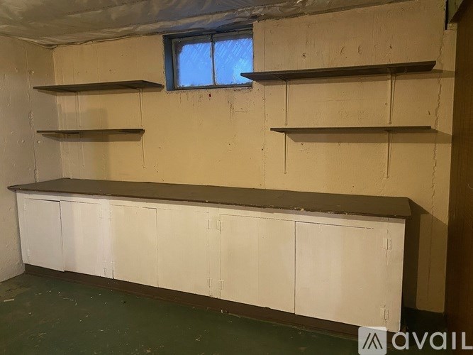 A room with a window, shelves, and cabinets.