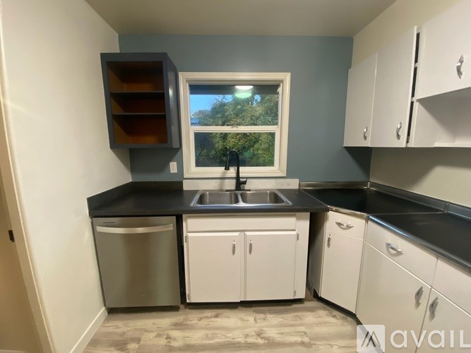 A kitchen with white cabinets and a black countertop.
