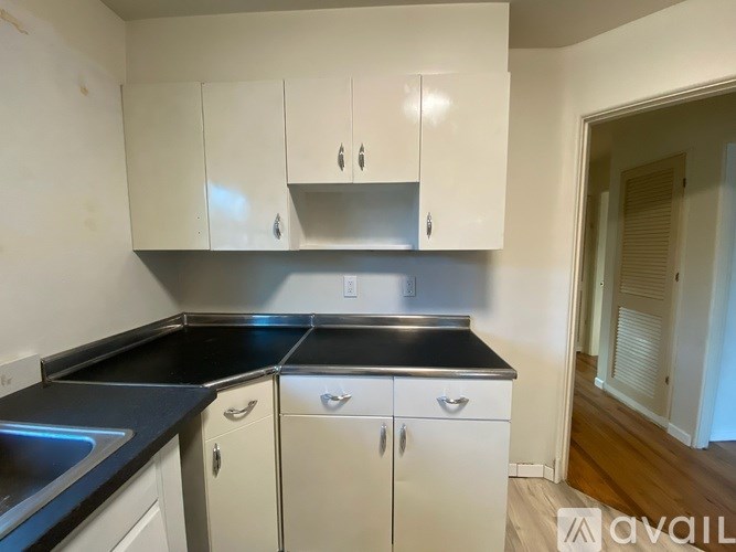 A kitchen with white cabinets and black countertops.