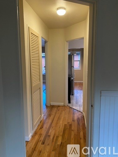 A hallway with wooden floors and white walls.