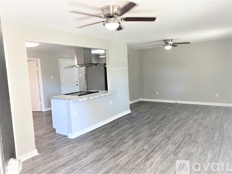 A spacious kitchen with a bar counter and a ceiling fan.