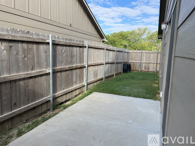 A backyard with a wooden fence and a concrete path.