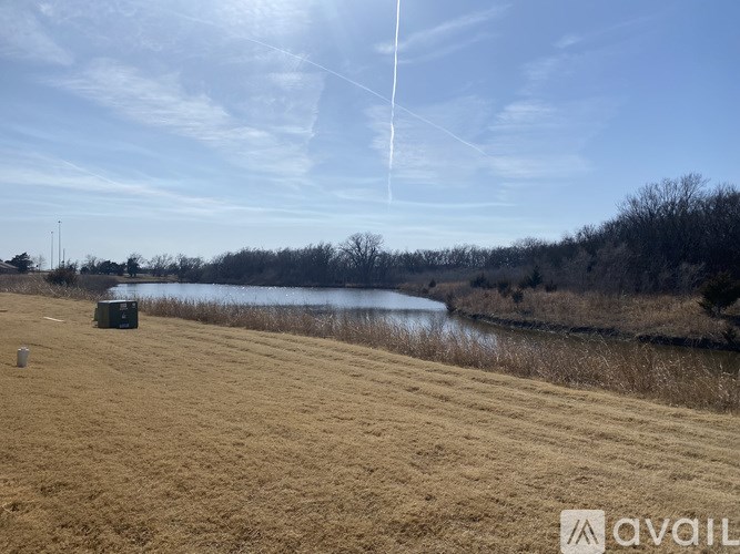 A field with a body of water and a clear sky.