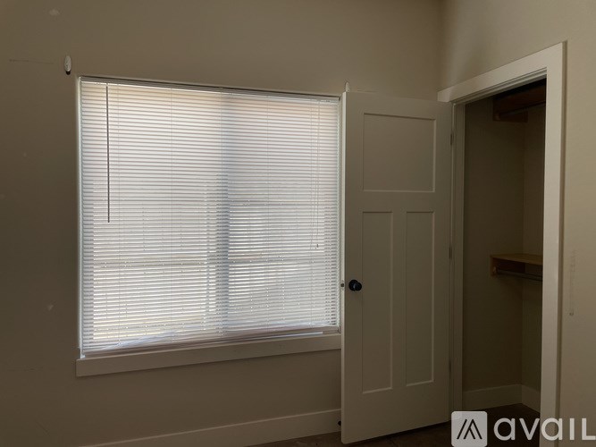 A room with a window covered by blinds and a door.