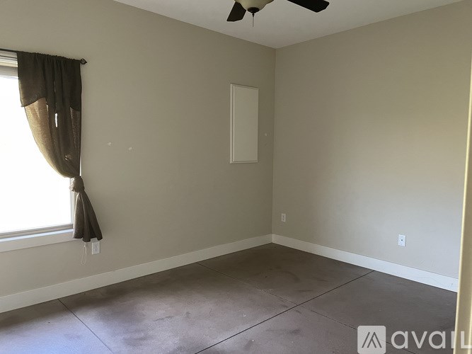 A room with a ceiling fan and a window with curtains.