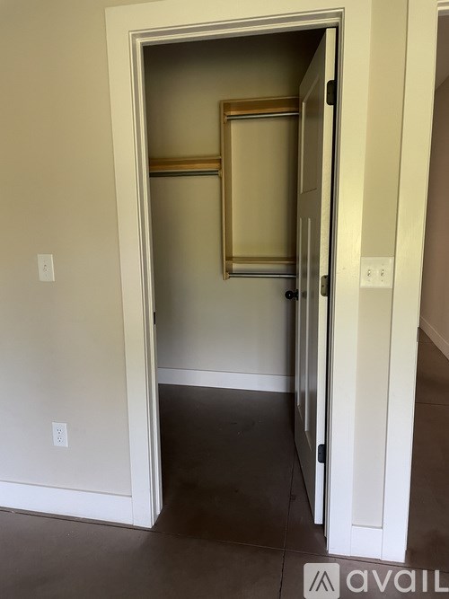 A white door is open to a room with a brown floor.