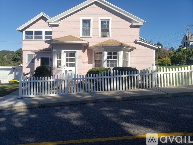 A pink house with a white picket fence in front.