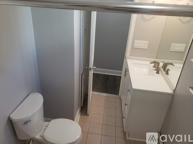 A white toilet is in a small bathroom with a sink and a shower.