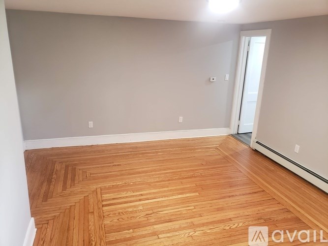 A room with wooden flooring and a doorway leading to another room.