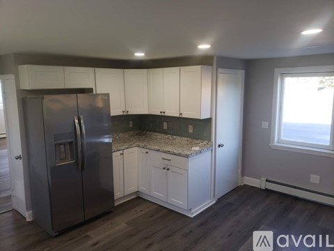A kitchen with a stainless steel refrigerator and white cabinets.
