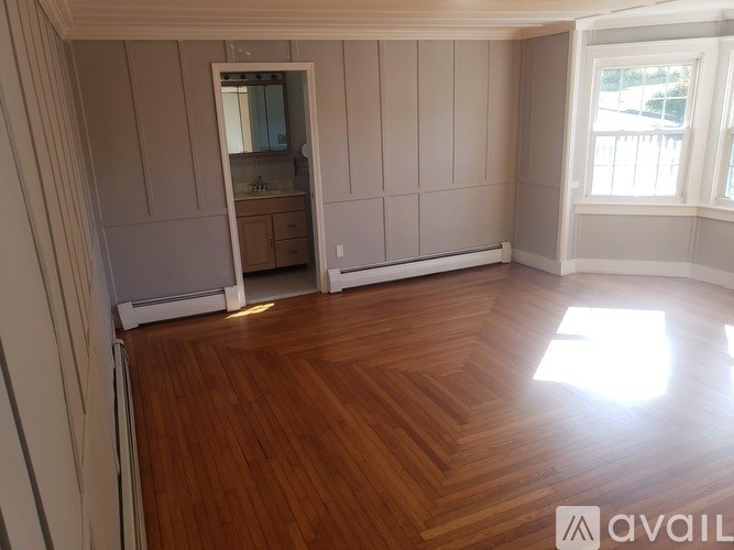 A room with wooden flooring and a large mirror on the wall.
