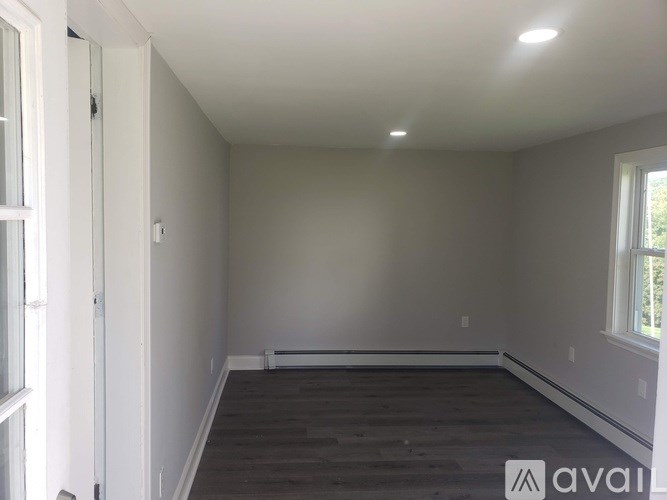 A room with a window on the right side and a door on the left side.