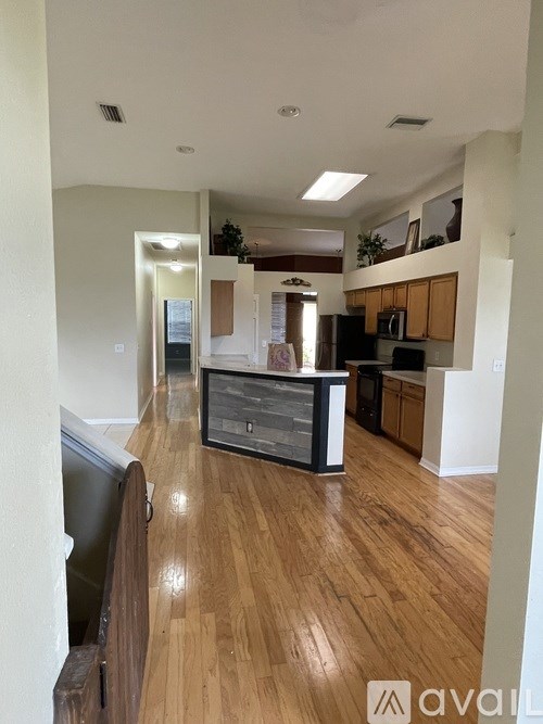 A kitchen with wooden floors and a black fridge.