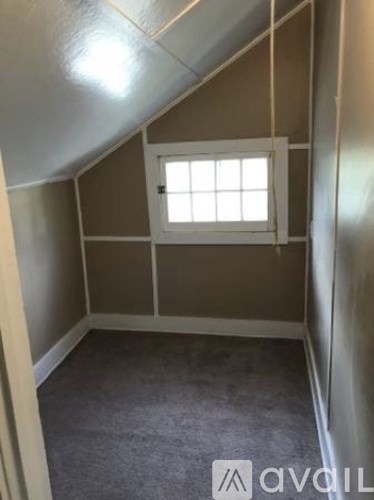 A small room with a window and a carpeted floor.