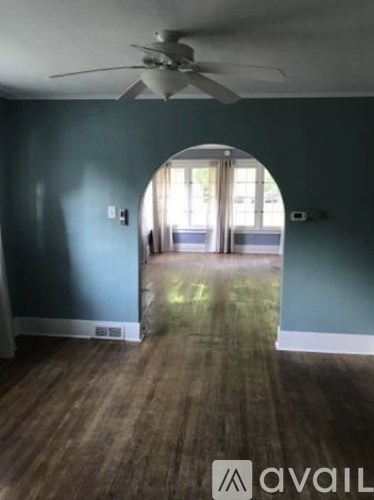 A room with a fan and a doorway leading to another room.