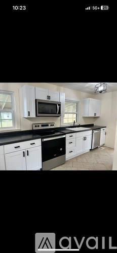 A kitchen with white cabinets and black countertops.