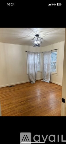 A room with wooden flooring and a window with curtains.
