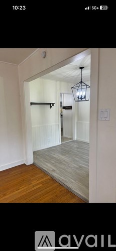 A room with wooden flooring and a chandelier hanging from the ceiling.