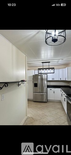 A kitchen with a stainless steel refrigerator and white cabinets.