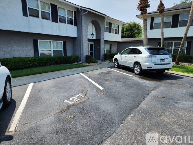 A white car is parked in a parking lot with the number 12 painted on the pavement.