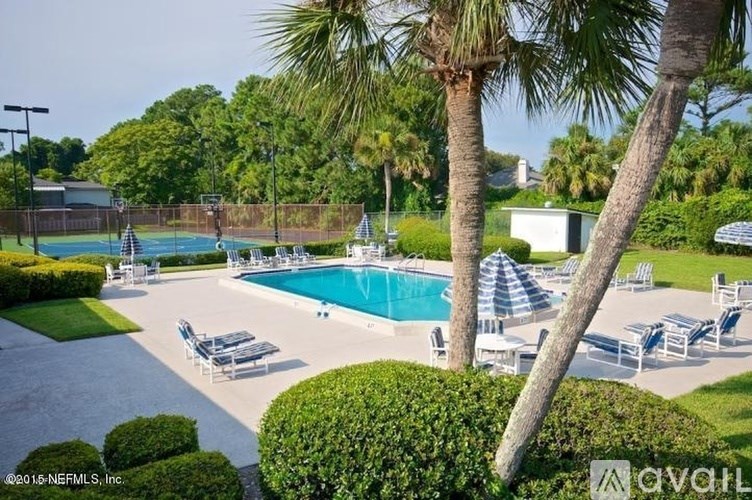 A pool surrounded by palm trees and lounge chairs.