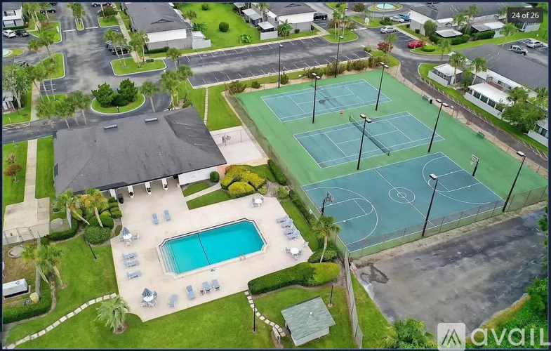 An aerial view of a tennis court surrounded by a pool and a parking lot.