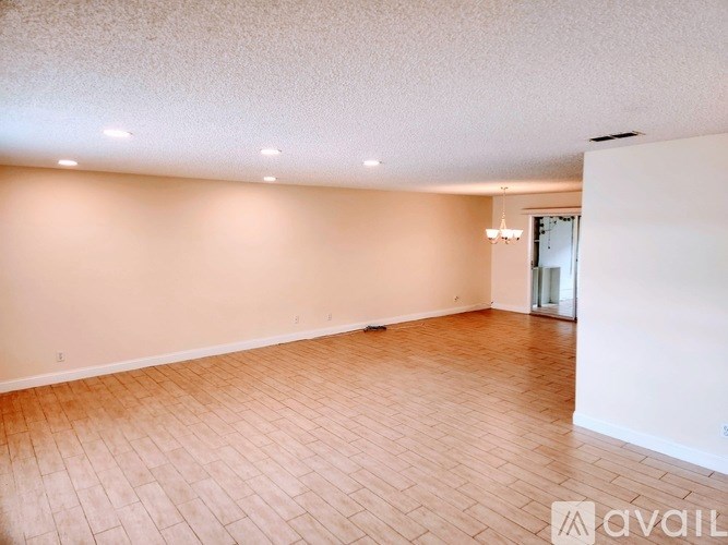 A spacious room with wooden flooring and a chandelier.