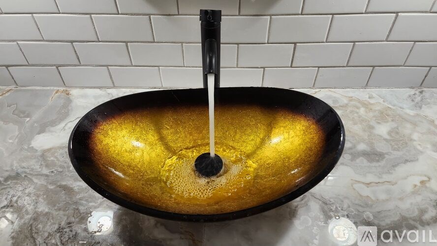 A black faucet with a yellow sink underneath it.