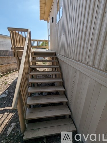A wooden staircase with a railing is in front of a wooden fence.