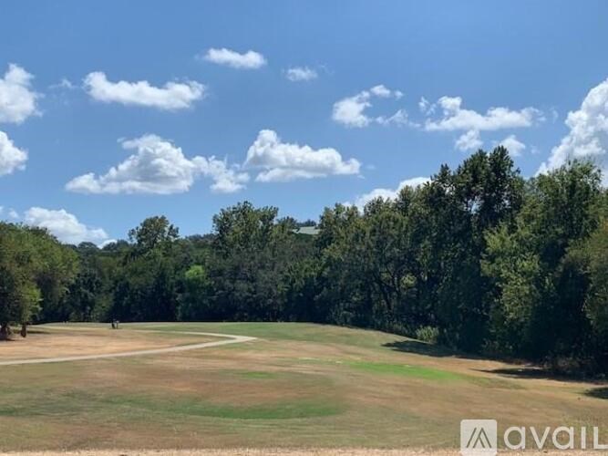 A grassy field with trees in the background and a clear blue sky.