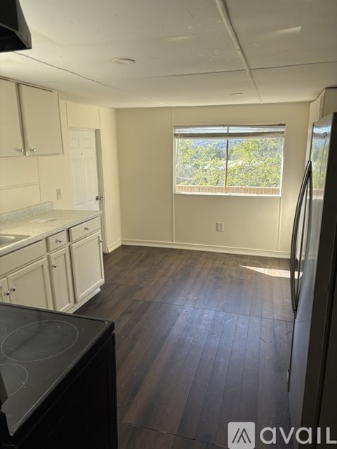 A kitchen with white cabinets and a black fridge.