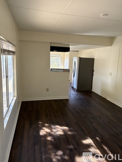 A room with wooden floors and a window on the left side.