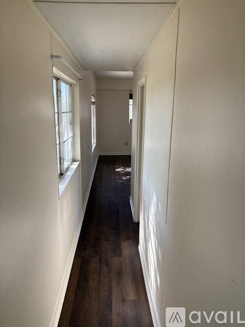 A long hallway with white walls and wood floors.