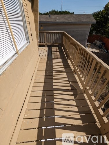 A wooden deck with a railing is being constructed on a house.