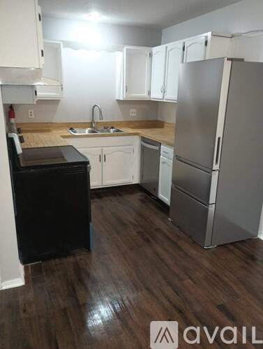A kitchen with a black fridge and white cabinets.
