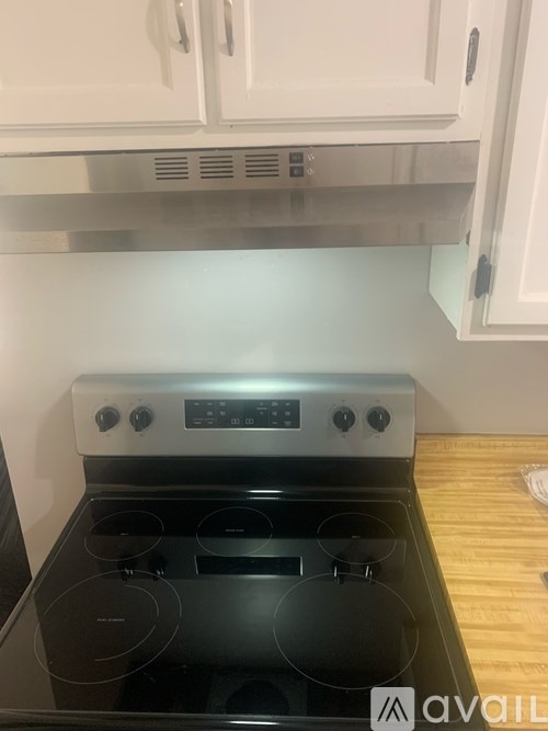 A modern kitchen with a stove top oven and white cabinets.