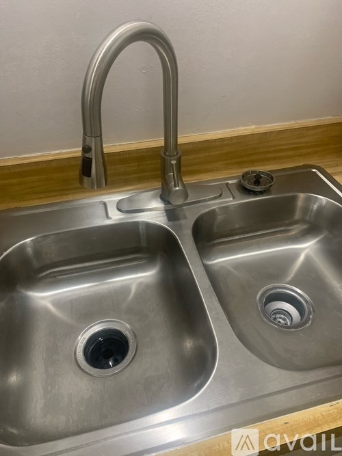 A double sink stainless steel kitchen sink with a pull down faucet.
