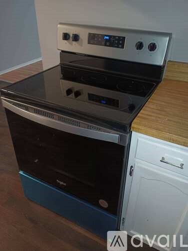 A modern stove with a digital control panel is placed on a wooden countertop.
