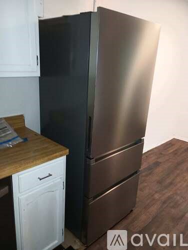 A stainless steel refrigerator stands next to a white cabinet.