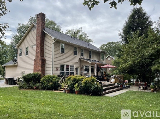 A house with a red umbrella is surrounded by greenery.