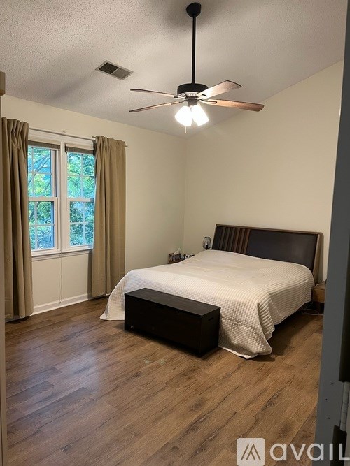 A bedroom with a bed, a ceiling fan, and a window with curtains.