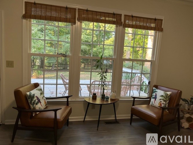 Two chairs and a table are in front of a window with a view of a backyard.