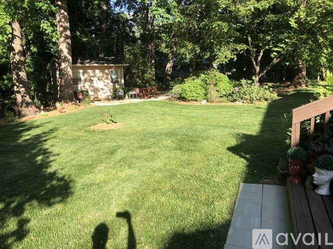 A backyard with a wooden deck and a green lawn.