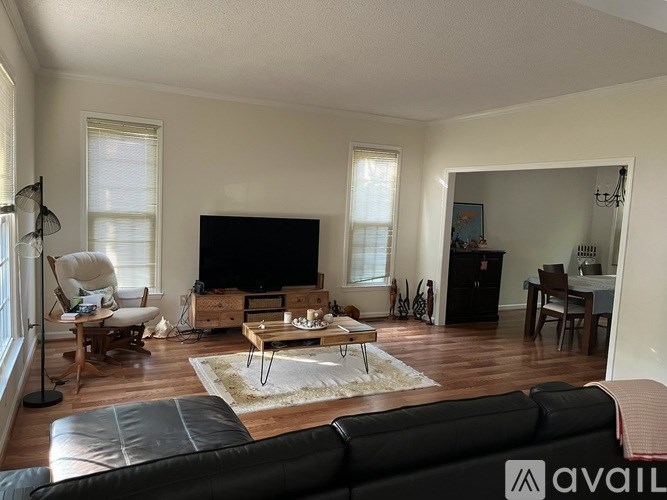 A living room with a black leather couch and a wooden coffee table.