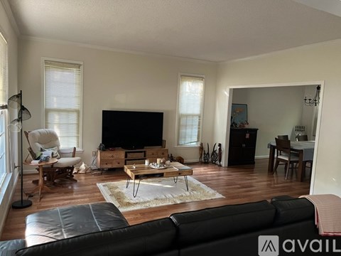 A living room with a black leather couch and a wooden coffee table.
